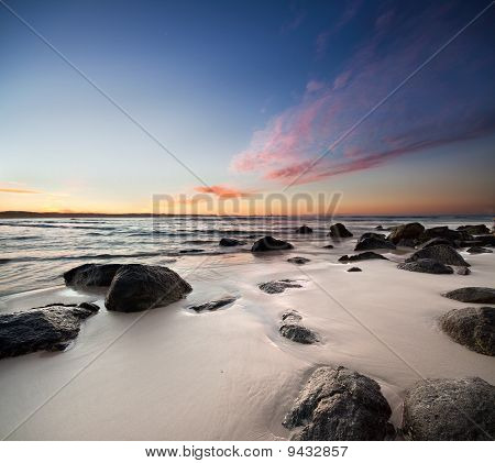 rocas en la playa con nube roja