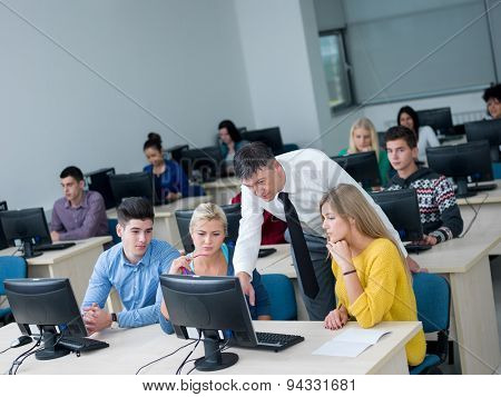 group of students with teacher in computer lab classrom learrning lessons,  get help and support