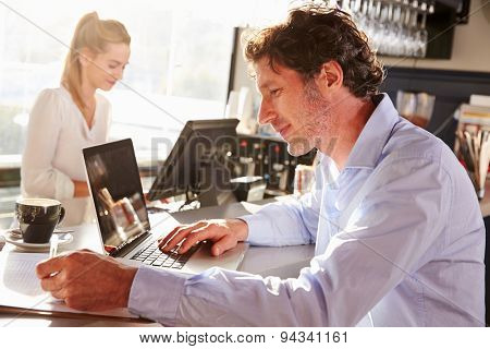 Male restaurant manager working on laptop