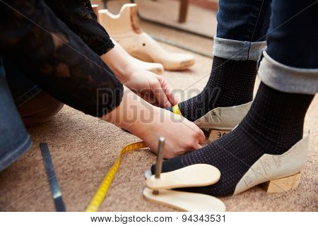 Shoemaker measuring customers feet, close up