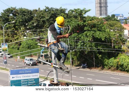 KOTA KINABALU, SABAH MALAYSIA - OCT 19,2016: Unidentified electircian repairing the overhead line fuse on top of electric post power pole