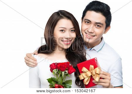 Asian man makes present to his lovely sweetheart. Young man giving a gift. Cheerful young couple man and woman at home offering to each other gifts for lover's valentine day