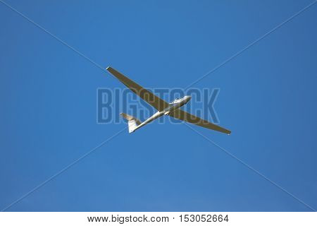 A sailplane in front of a blue sky glides through the air without its own motor drive.