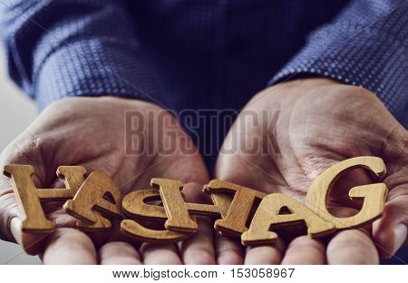 wooden letters forming the word hashtag placed in the hands of a young caucasian man