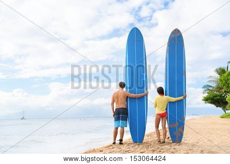 Two people young couple surfers standing with long blue surfboards on hawaii Kaanapali beach after surf class. Fun surfing sport activity on Maui touristic beach for summer vacations.