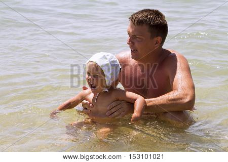 man father and daughter a little girl swimming in the sea in the waves splashing happiness joy laughter summer vacation