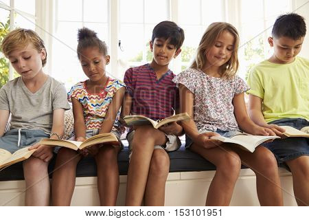 Group Of Multi-Cultural Children Reading On Window Seat