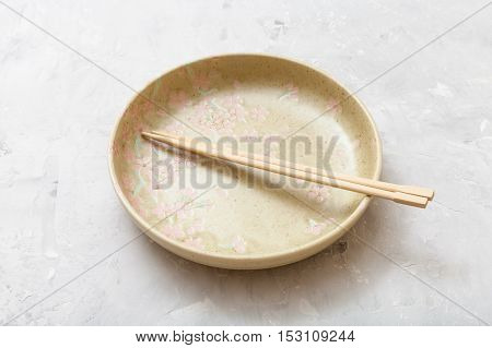 Yellow Plate With Chopsticks On Gray Concrete