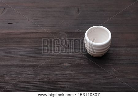 White Cup For Sake On Dark Brown Wooden Table