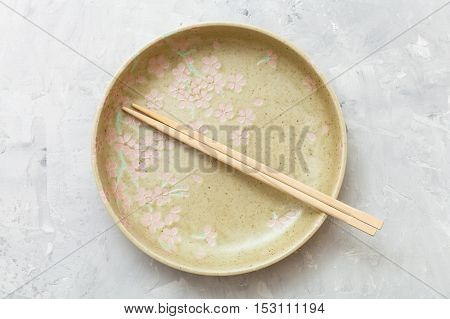 Top View Yellow Plate With Chopsticks On Concrete