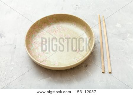 Yellow Plate And Chopsticks On Concrete