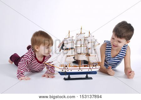 boy and girl playing with ship on white