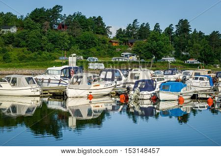 Fishing boats moored at calm lake shore. Norway.