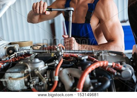Cropped image of a repair man hands fixing engine on a plane