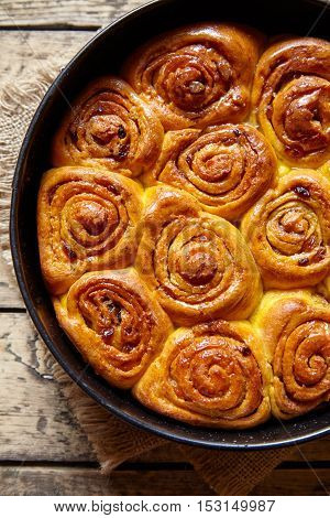 Pumpkin cinnamon dough bun rolls traditional baked vegan sweet autumn cake holiday dessert swirl bread food on vintage wooden table background