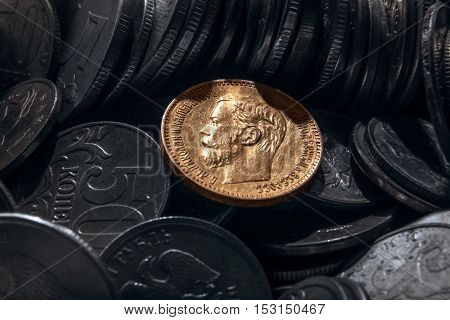 coin from precious metal of gold against the background of coins of small advantage from cheap metals.