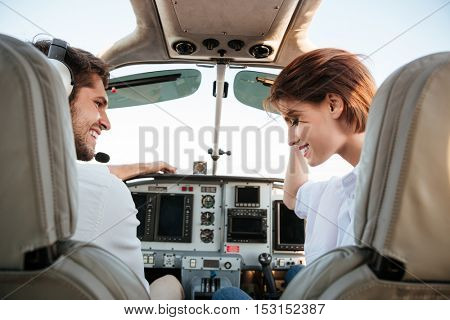 Beautiful young couple looking at each other while sitting inside airplane cabin