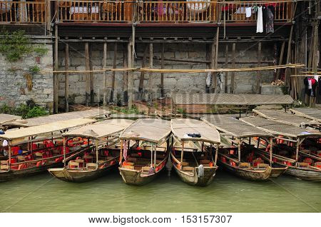 Chinese tourists boats docked along a bank of the Tuo Jiang River in the village of Fenghuang China in Hunan province.