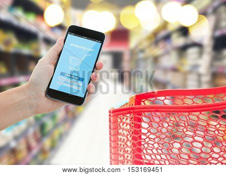 hands holding mobile smart phone with mobile shop, comercial center with red cart in background