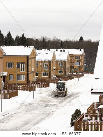 excavator cleans snow road in the cottage winter