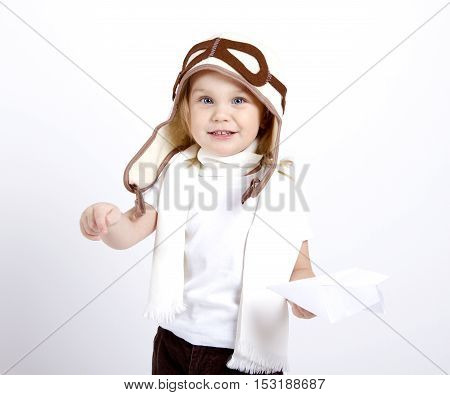 happy kid playing with paper airplane. studio photo. aviator hat and scarf