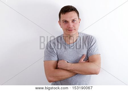 Happy young man. Portrait of handsome young man in casual shirt keeping arms crossed and smiling while standing against white background