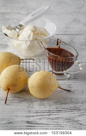 Pears with chocolate sauce on white wooden table