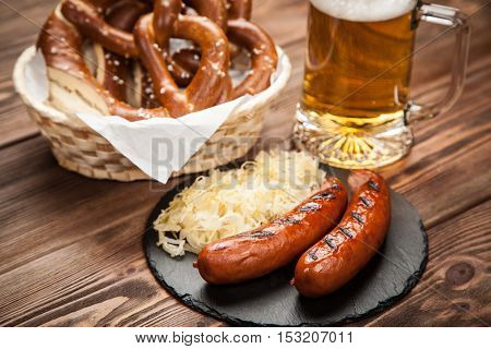 Pretzels, bratwurst and sauerkraut on wooden table
