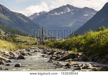 Spol River With Church Of Santa Maria In Livigno, Italy