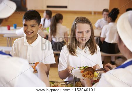 Over shoulder view of kids being served in school cafeteria