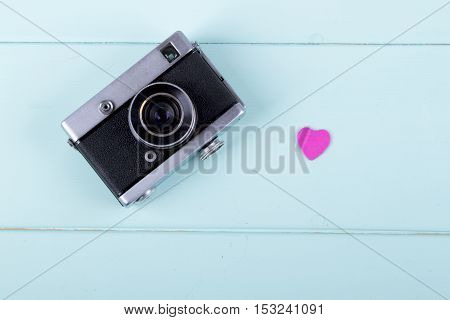 Retro Camera with pink heart on a wooden background