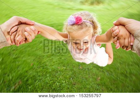 Close up portrait of little girl being spun in circles at park by her father