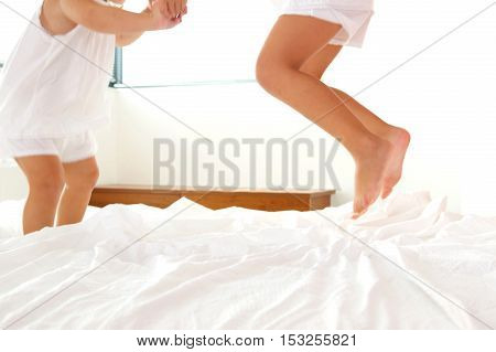 Low section portrait of two little girls jumping on bed