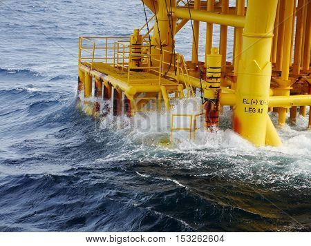 High wave hitting the Boat Landing and Producing Slots at Offshore Platform during bad weather conditions (high wave) - Oil and Gas Industry