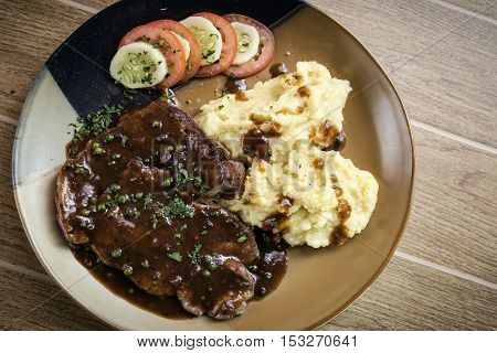 beef steak meal with mashed potato and gravy sauce on table