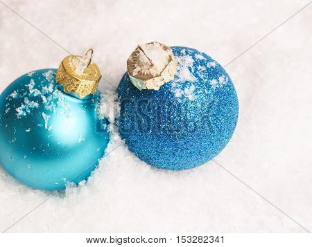 Two blue Christmas baubles on a snow background