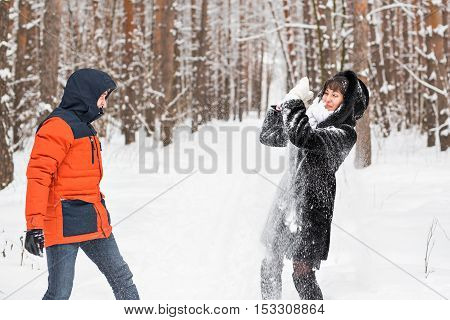 Snowball fight. Winter couple having fun playing in snow outdoors