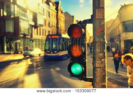 Pedestrians and tram at the crossroads with traffic lights in the city against the backdrop of facades of houses and tram rails in Riga