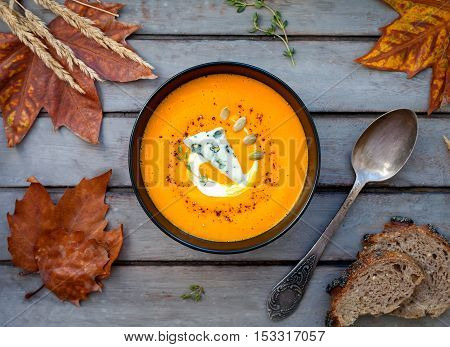 Hot pumpkin soup with blue cheese, herbs and multi-cereal bread on a wooden table. View from above