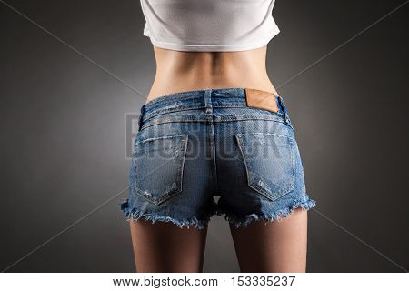 Sexy butt in denim shorts. Studio portrait black background.