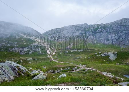 Scenic hiking path to famous Kjerag stone through the rocks and hills. Lysefjord, Norway.