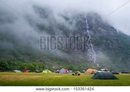 Tents at Lusebotn camping with amazing view on the rocky mountain in fog and high waterfall. Lysefjord, Norway.