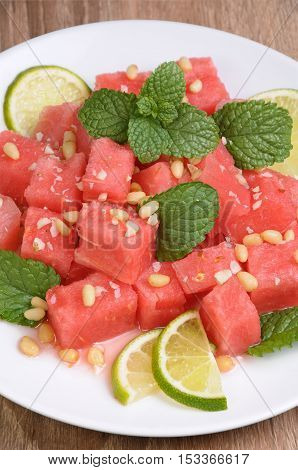 A refreshing salad of watermelon cubes with slices of lime mint peanuts pine nuts