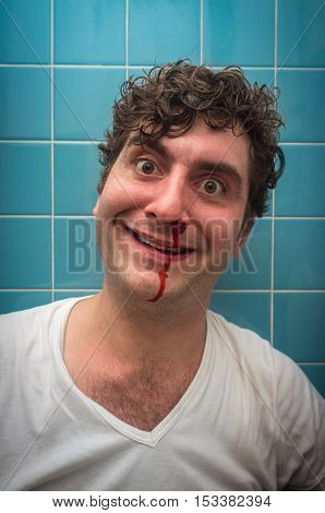 Curly haired man in bathroom with bad nose bleed