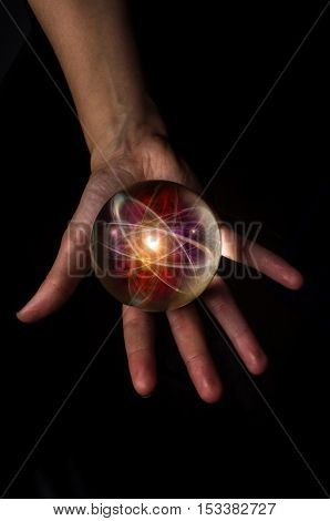 Female hands hold crystal ball with atom particle for fortune telling background