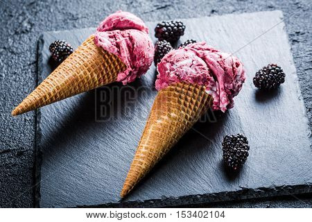 Tasty ice cream with berry fruits in waffels on black rock