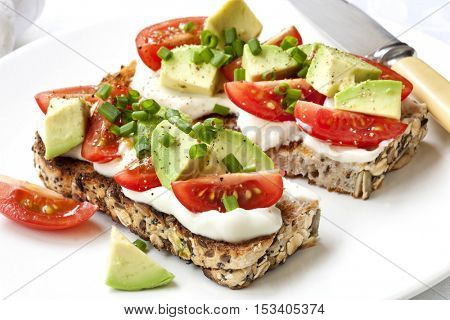 Avocado, cream cheese and tomatoes on wholewheat toast.  Topped with chives.