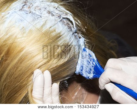 Hairdresser is hair dying some blonde hair.