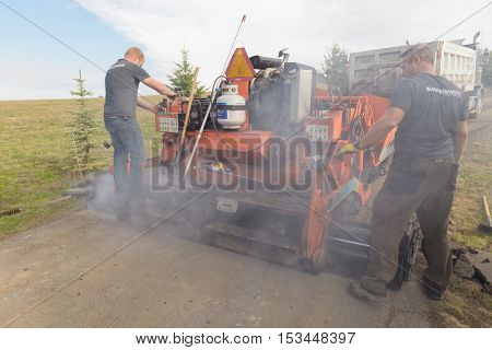Colbert, WA - October 24, 2016: Workers of Black Diamond Asphalt Paving, LLC., repairing patches in a private road/driveway