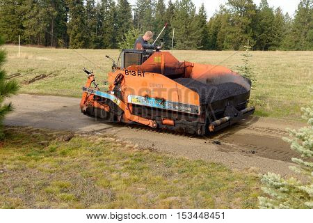 Colbert, WA - October 24, 2016: Workers of Black Diamond Asphalt Paving, LLC., repairing patches in a private road/driveway